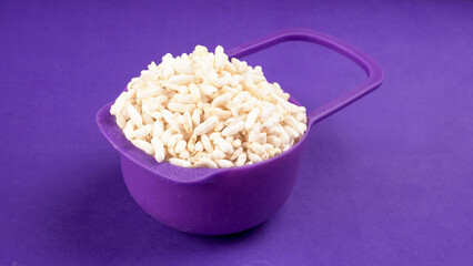 puffed rice inside wooden bowl with puffed rice resting on white background with top view