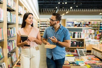 Smiling couple talking about books while buying novels at the shop