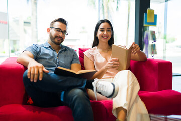 Attractive smiling couple enjoying a book relaxing on the sofa
