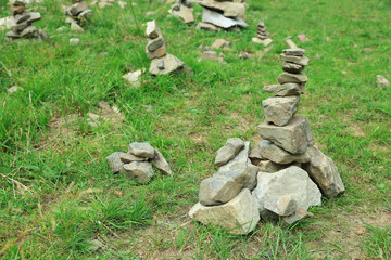 Many stacked stones on green grass outdoors, space for text