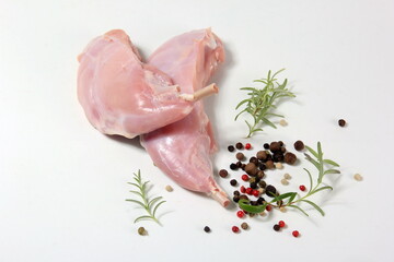 raw rabbit legs with bone with peppercorns on a white background
