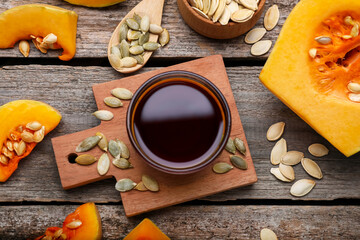 Flat lay composition with fresh pumpkin seed oil in glass bowl on wooden table