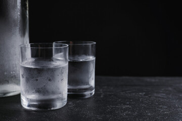 Vodka in shot glasses on table against black background. Space for text