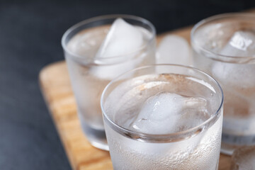 Shot glasses of vodka with ice cubes on table, closeup