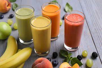 Many different delicious smoothies and ingredients on grey wooden table