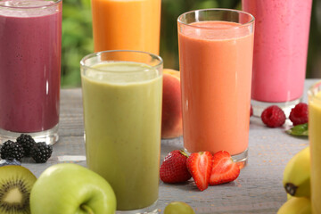 Many different delicious smoothies and ingredients on grey wooden table, closeup