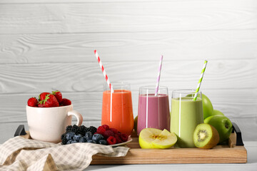 Glasses of different tasty smoothies and fresh ingredients on white wooden table