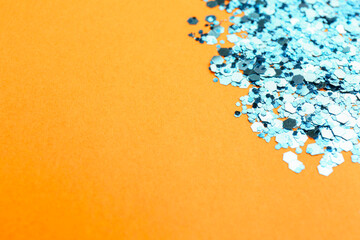 Shiny bright light blue glitter on pale orange background, closeup. Space for text