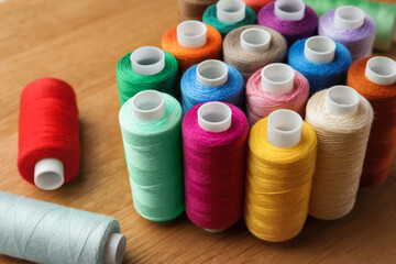 Many colorful sewing threads on wooden table