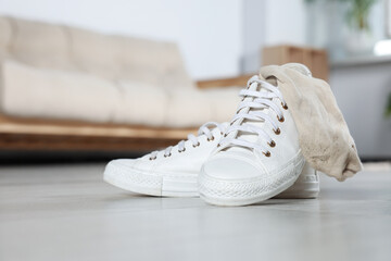 Sneakers with dirty socks on white wooden floor indoors - obrazy, fototapety, plakaty