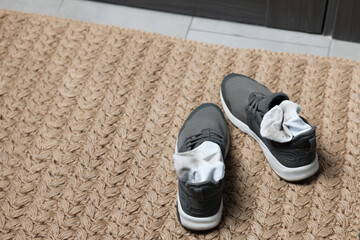 Sneakers with dirty socks on woven mat indoors, closeup. Space for text