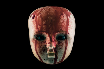 Creepy bloody doll head isolated on black background with clipping path