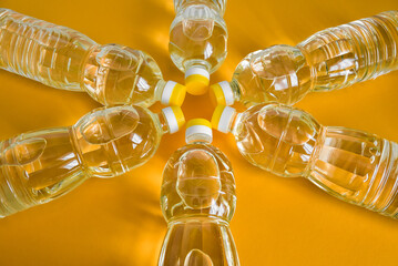 Plastic bottles with natural refined sunflower oil on orange color background