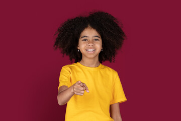 Cute black girl pointing at camera, isolated on colorful background