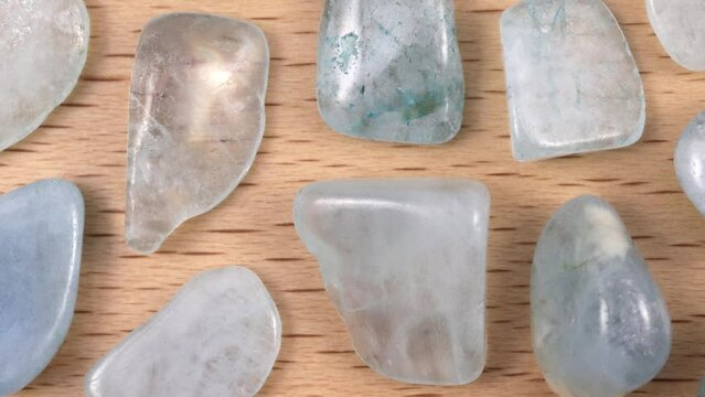 Aquamarine rare jewel stones texture on light varnished wood background. Moving right seamless loop backdrop.