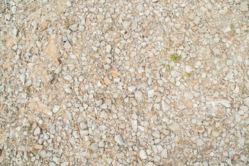 Background with gravel and grass growing between the stones. Small pieces of granite scattered on the ground.