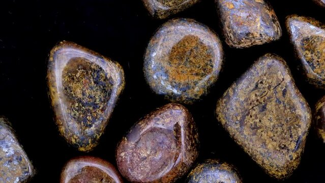 Bronzite heap up jewel stones texture on black background. Moving right seamless loop backdrop.