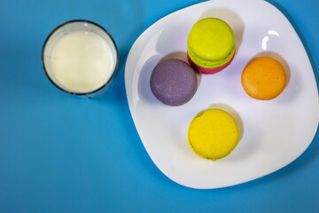Assortment of delicate colorful macaroons and a glass of milk