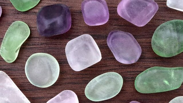 Fluorite rare jewel stones texture on brown varnished wood background. Moving right seamless loop backdrop.