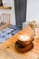 Brown cup of cappuccino with beautiful latte art on wooden table background.