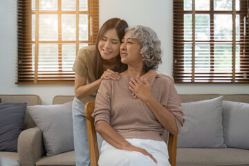 Loving adult daughter hugging older mother on couch at home, family enjoying tender moment together, young woman and mature mum or grandmother looking at each other, two generations