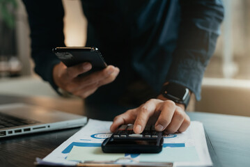 Male businessman working on desk office with using a calculator to calculate.