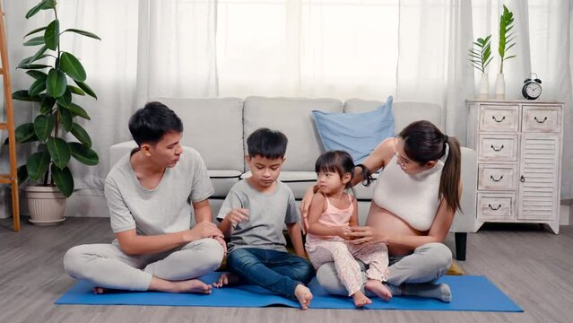 4K, Asian family of parents, sons and daughters are happily relaxing in the middle of house, Beautiful teenage mother who is pregnant with a big belly near giving birth plays with her daughter.