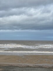 Fototapeta na wymiar Waves crashing onto the beach and sea wall during high tide. Taken in Cleveleys Lancashire England. 