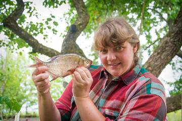 Large bream in women's hands. Girl on a fishing trip.