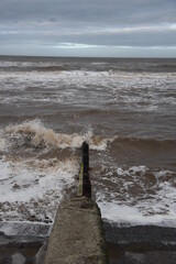 Waves crashing onto the beach and sea wall during high tide. Taken in Cleveleys Lancashire England. 
