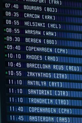 Vertical of a timetable of departures in Lech Walesa airport in Gdansk, Poland. - obrazy, fototapety, plakaty