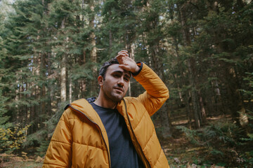 Man walking in the forest in autumn in a yellow jacket. Hiking concept.