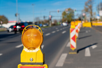 Orange signal lamp on the carriageway of the highway enclosing the construction site. Selective focus. Close up. - obrazy, fototapety, plakaty