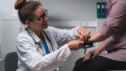 Young female doctor attach robotic hand prosthesis to young disabled man
