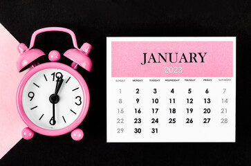 The January 2023 Monthly calendar year with alarm clock on pink and black background.