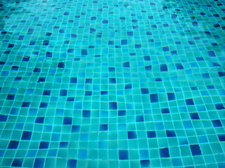 Modern turquoise  blue sky ceramic. Mosaic tiles in various shades of blue in the swimming pool. Ripple Water in swimming pool with blue tile floor background. 
