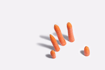 Five carrots like the fingers of a hand on a white background.