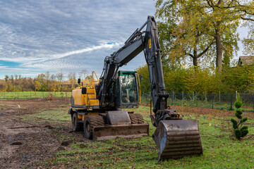 Big yellow excavator on the land for the construction of a new house.