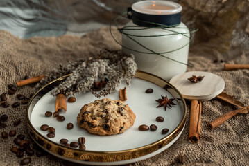 An elegant composition of candles, plates with a golden border, cookies and spices - anise, cinnamon and coffee. Against the background of burlap