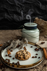 An elegant composition of candles, plates with a golden border, cookies and spices - anise, cinnamon and coffee. Against the background of burlap