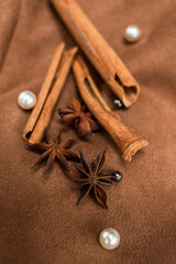 An elegant composition of spices - with anise, cinnamon on a suede brown background with beads and pearls