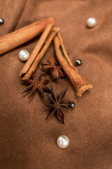 An elegant composition of spices - with anise, cinnamon on a suede brown background with beads and pearls