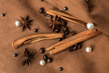 An elegant composition of spices - with anise, cinnamon on a suede brown background with beads and pearls