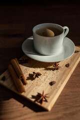 A cup of coffee with cane sugar and cinnamon sticks