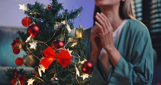 A beautiful woman is decorating a pine tree for a Christmas party at home.