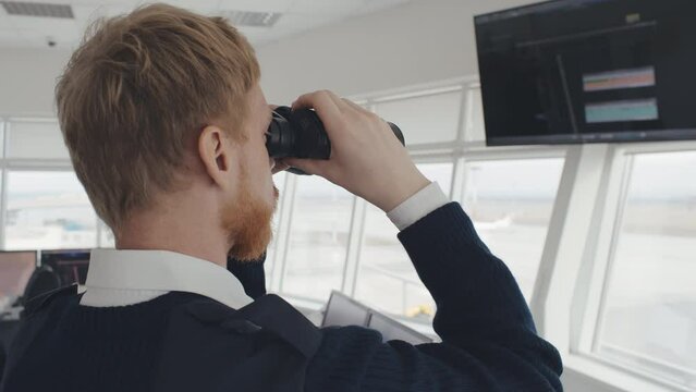 Close up of surveillance officer with binoculars working in traffic control tower. Realtime