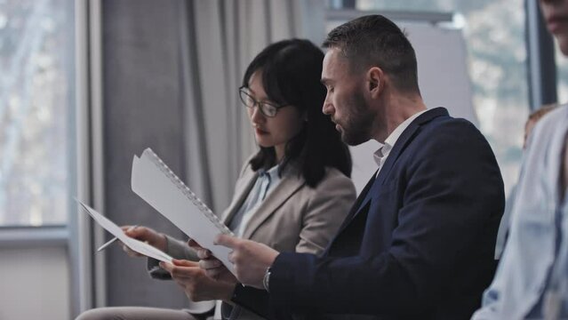 Two modern investors holding papers with data discussing presentation of new business project