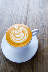 white cup of cappuccino on wooden background with beautiful latte.