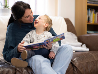 Happy boy reading with mother on sofa