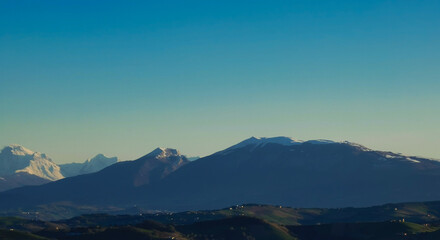 Fototapeta na wymiar Monti Appennini innevati nel cielo azzuro di una giornata di sole invernale